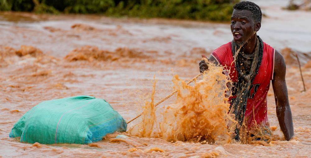 En man i kenyanska Tula korsar en översvämmad väg.